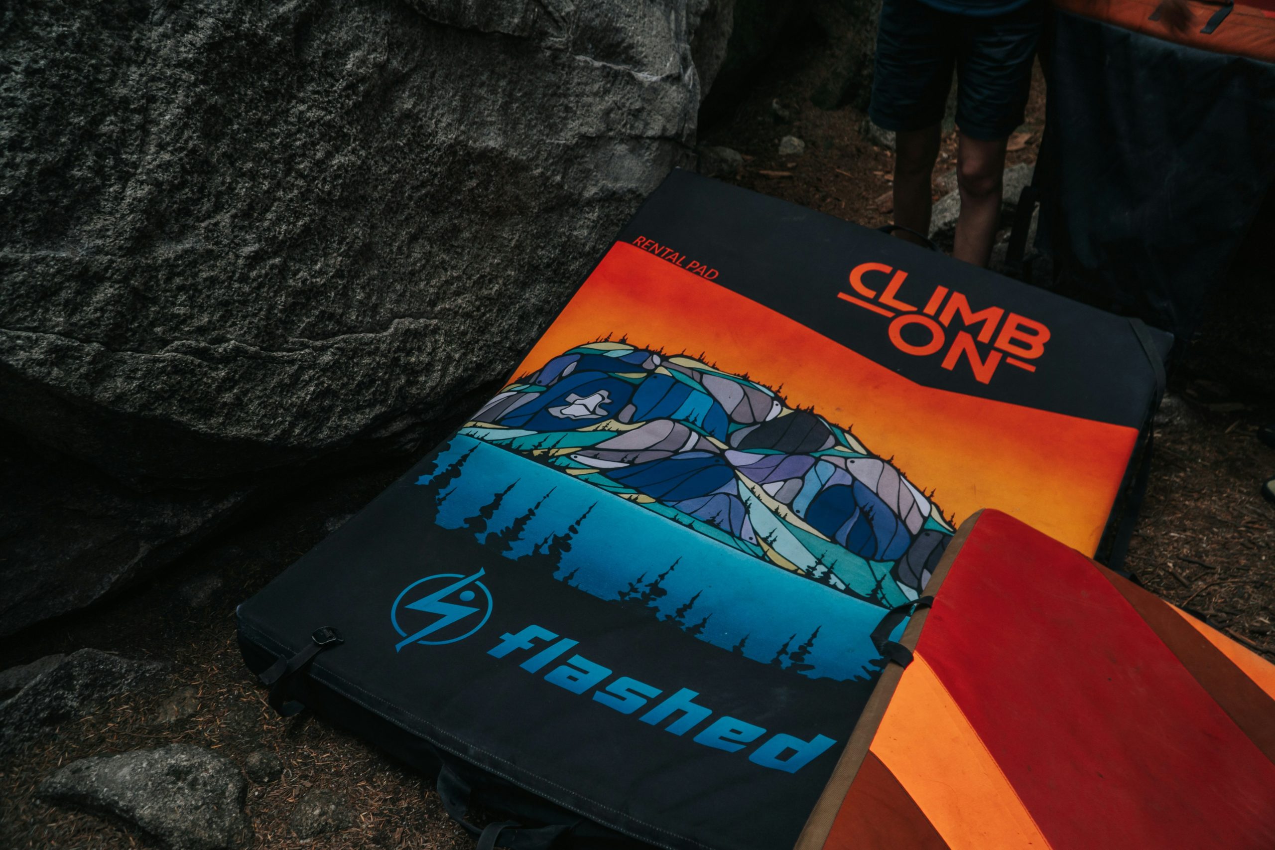 A climber wearing protective gloves scaling a rugged cliff under a clear blue sky